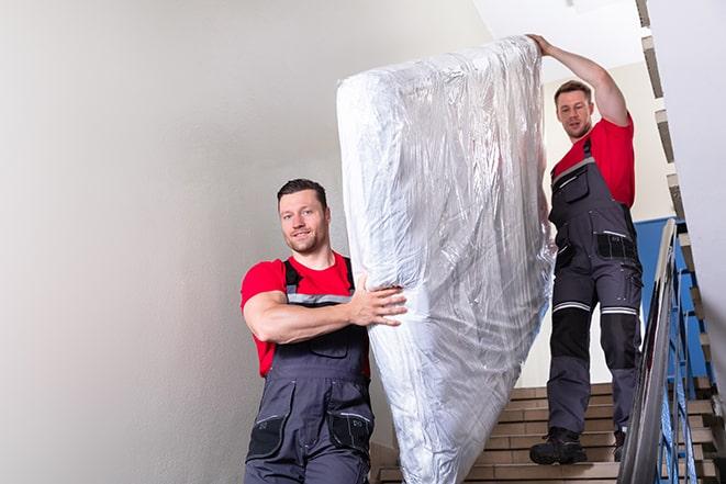 team carrying a large box spring out of a bedroom in Oakland Park, FL